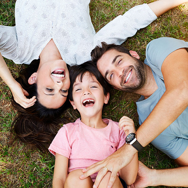 Family laying in the grass and smiling